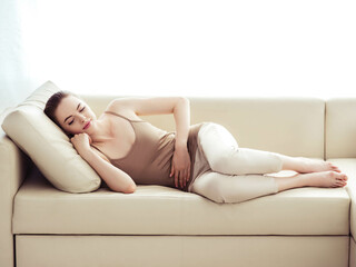 Obraz premium Stomach pain woman home bad lying on the sofa