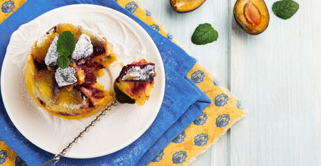 Homemade plum clafoutis or pudding on white ceramic plate. Rustic homemade plum bakery products Selective focus.