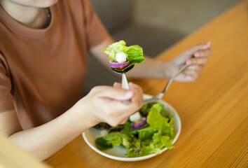 Close up of young woman eating salad at restaurant with feeling happy and enjoy to eat. To lose weight and diet. Weight loss concept.