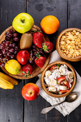 Corn flakes with yogurt and chia seeds. Assorted juicy ripe fruits. Strawberry, kiwi, apple, pear, banana, grapes. Delicious tropical fruits on a wooden background. Healthy breakfast concept
