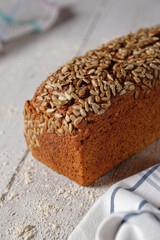 A loaf of wholemeal spelt bread, a box bread with a grain crust. Close-up view on gray wooden table.
