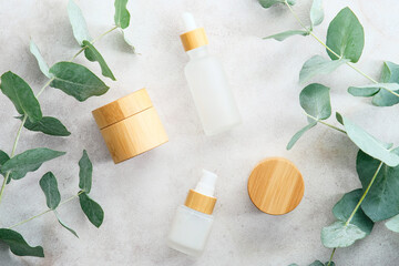 Eco natural cosmetics products set in transparent and bamboo containers on marble stone background with eucalyptus branches. Flat lay, top view. Beauty products packaging design, branding.