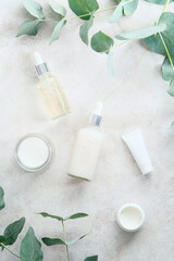 Obraz na płótnie Canvas Set of natural cosmetics in transparent containers on marble background with eucalyptus branches. Skin care beauty products design, branding.