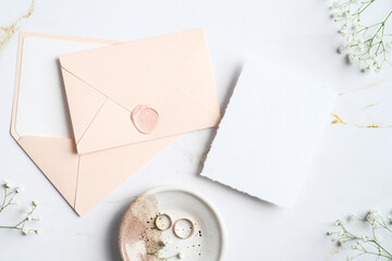 Wedding stationery top view. Flat lay pastel pink envelopes, wedding invitation card, rings,...