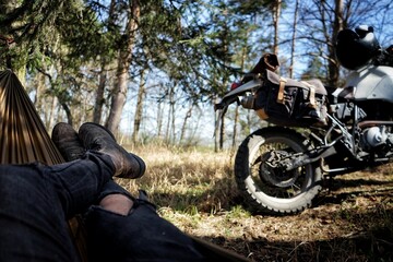 Guy resting in a hammock with an adventure motorcycle next to him