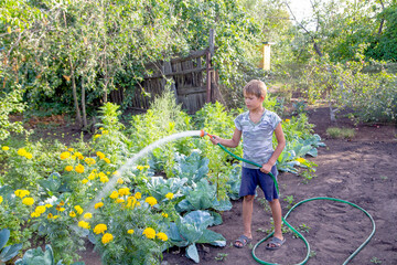 boy watering with a hose in the garden