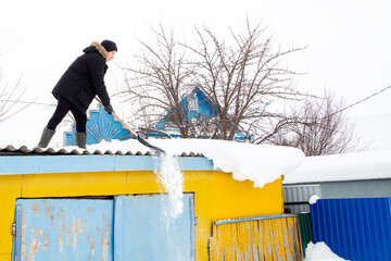 young guy throws snow off the roof
