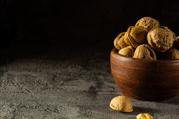 Whole walnuts in vintage bowl on black background