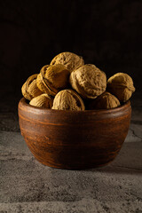 Whole walnuts in vintage bowl on black background