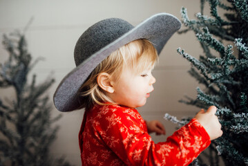 Baby girl looking at Christmas tree with hat