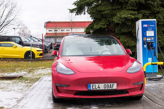 Roznov Czech Republic November 20th 2022 - Tesla model S car being charged with a yellow mussle car in background