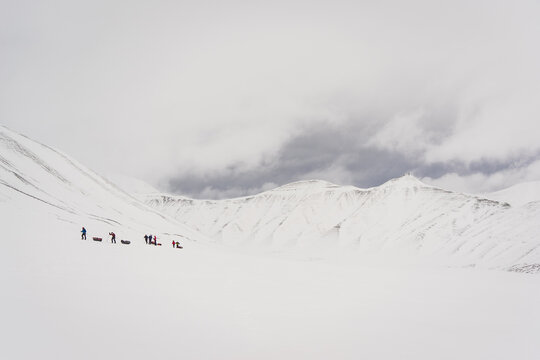 An expedition team climbs up a ridge through the snow