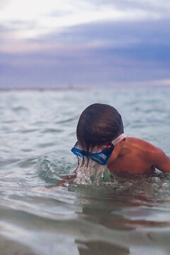 Boy wearing goggles playing in the ocean in Mexico.
