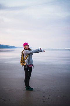 Solo Female Traveler in awe on Oregon beach at sunrise
