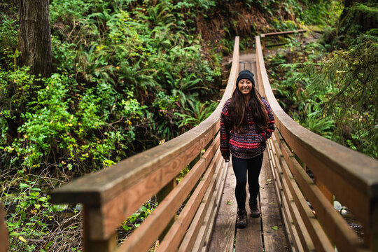 Smiling Young Woman crossing bridge on Oregon nature trail