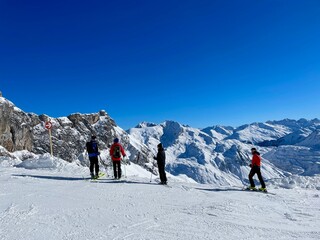 Fototapeta na wymiar Skiers taking a break and looking at pistes, ski slopes and mountains of noble skiing resort Lech Zuers, part of the Arlberg ski area. Vorarlberg, Austria.