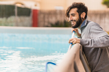 smiling hipster man doing pool maintenance at home