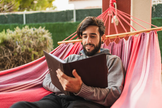 relaxed hipster man in hammock reading a book