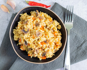 Vegetarian pilaf with mushrooms and fork on light background with gray textiles