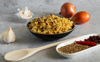 Pilaf with mushrooms and ingredients for it on a light background. Horizontal.