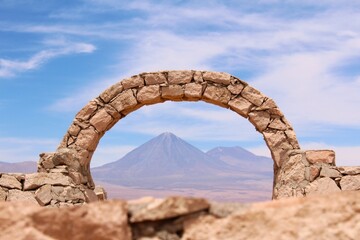 Stone arch at Pukara de Quitor - fortress at Atacama desert and Licancabur volcano on the...