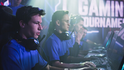 Anxious young cyber sportsman player preparing to play video game while sitting near team at start of professional gaming tournament