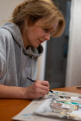 Young woman working on watercolor painting of cityscape