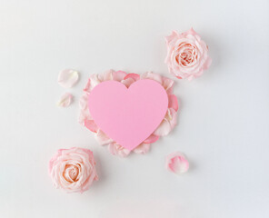 Valentine's Day background. Creative layout with pink flowers, paper heart over punchy pastel background. Top view, flat lay. Spring, summer or garden concept. Present for Woman day. 