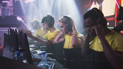 Esportsman gamer woman putting on headset and speaking with black man at start of video game match during professional esports championship