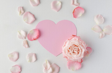 Valentine's Day background. Creative layout with pink flowers, paper heart over punchy pastel background. Top view, flat lay. Spring, summer or garden concept. Present for Woman day. 