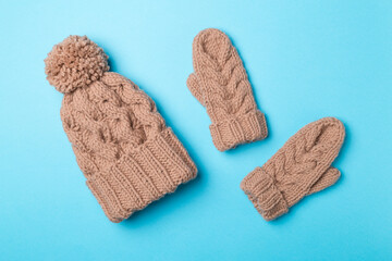 Brown winter hat and mittens on color background. Top view