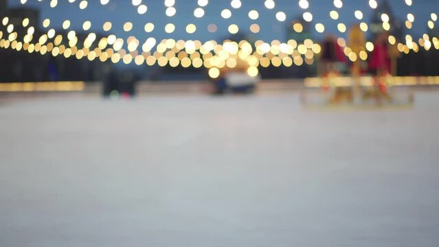 Blurred Ice resurfacer machine prepare ice on ice skating rink on Central square of the Kharkov city Christmas Holiday evening downtown. Winter in big city. Light lamp garland ornament