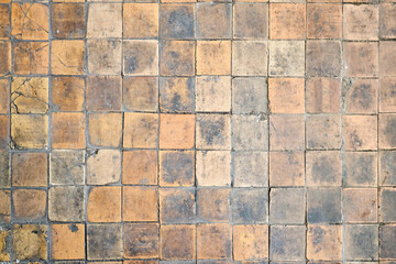 Orange brown white beige old shabby worn out floor tiles with damages cracks dirt caverns potholes and paint stains. Art retro grunge design background texture.