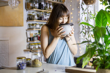 Young woman in a blue dress make a herbal tea.