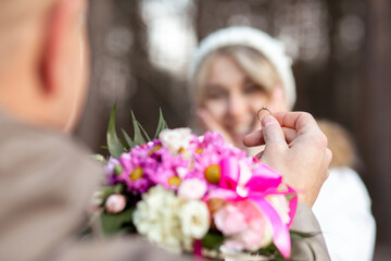 Fototapeta premium Portrait of two people couple smiling happy woman and man proposal holding bouquet of flowers together outdoors blur