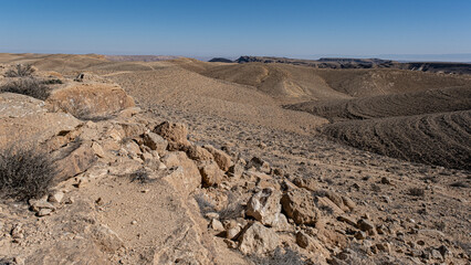 View of the Ramon Crater in the far background  from Mount Ramon, 1057 m ASL, located in the Negev Desert, near the Egyptian border and West of the Ramon Crater, Negev Desert, Mitzpe Ramon, Israel - obrazy, fototapety, plakaty