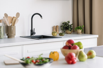 Modern black sink, kitchen appliances and salad ingredients