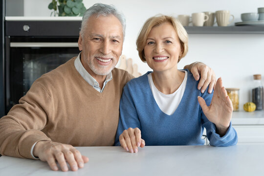 Smiling senior couple looking at camera when sitting at table
