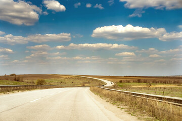 Wavy asphalt road on a background of blue sky and white clouds