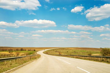 Wavy asphalt road on a background of blue sky and white clouds