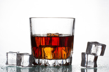 A glass with whiskey and ice on a white isolated background. Scattered ice and slowly melting. Fresh young whiskey