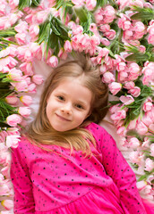Fototapeta premium Portrait of a cute little girl with flowers in a pink dress. Girl lady in flowers. Mother's Day, top view. Spring portrait.