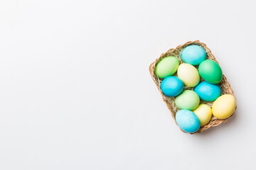 Multi colors Easter eggs in the woven basket on colored background . Pastel color Easter eggs. holiday concept with copy space