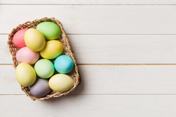 Multi colors Easter eggs in the woven basket on colored background . Pastel color Easter eggs. holiday concept with copy space