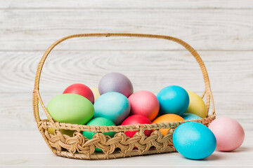 Multi colors Easter eggs in the woven basket on colored background . Pastel color Easter eggs. holiday concept with copy space