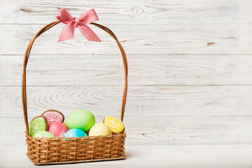 Colorful easter cookies in basket with Multi colors Easter eggs on colored background . Pastel color Easter eggs. holiday concept with copy space