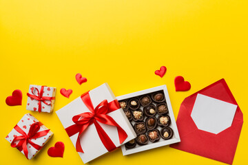 Envelope on colored background for Valentine Day with gift box and chocolate. Heart shaped with gift box of chocolates top view with copy space