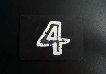 The number 4 is written in white on a black plate lying on a black table