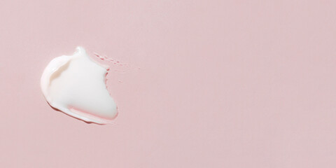 Smear of cream on a pink background.