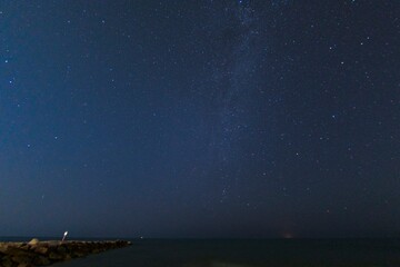 Sea with starry night sky seen from the cliff
